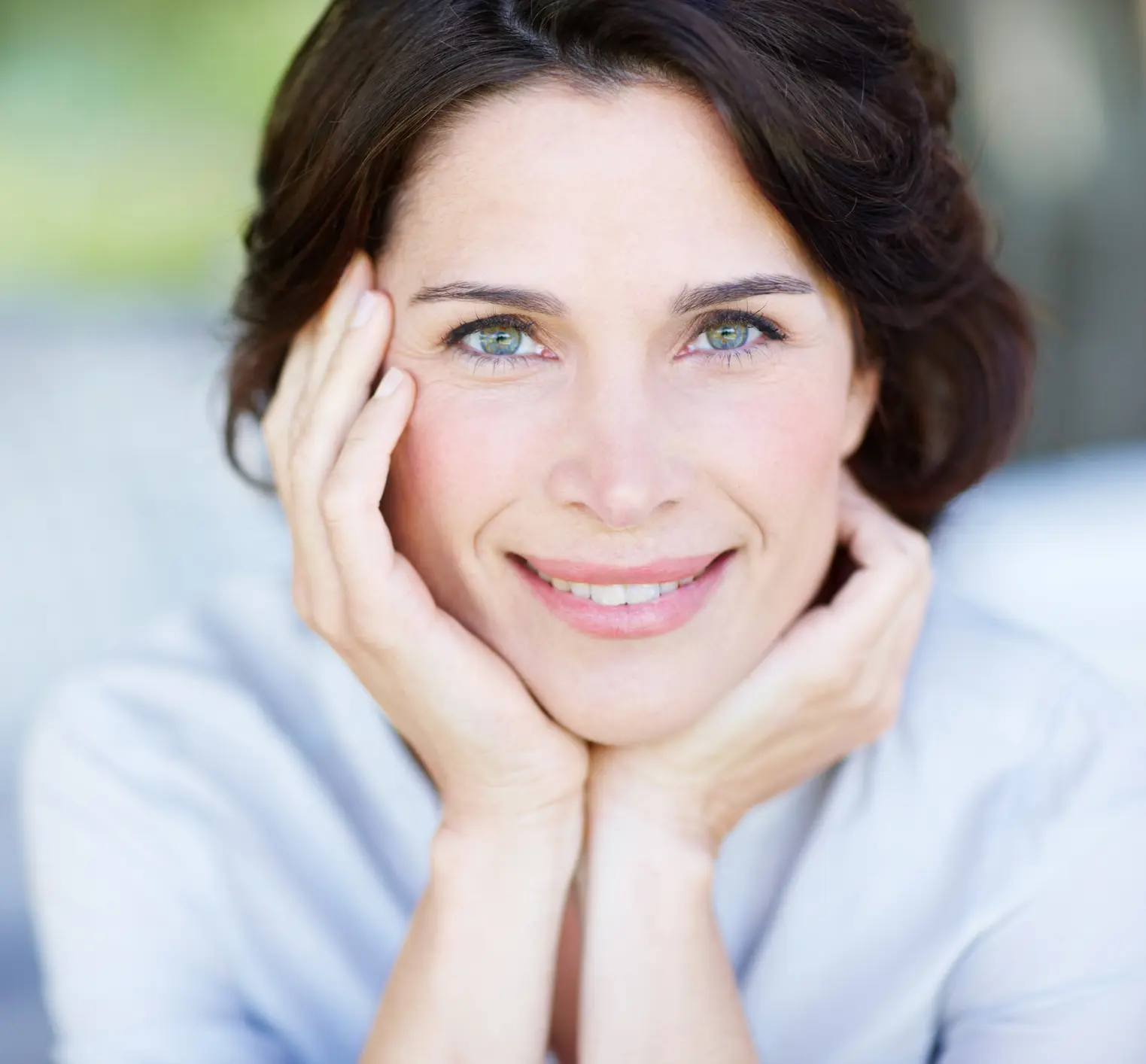 an attractive middle-aged woman with her hands on your cheeks, smiling and looking at the camera