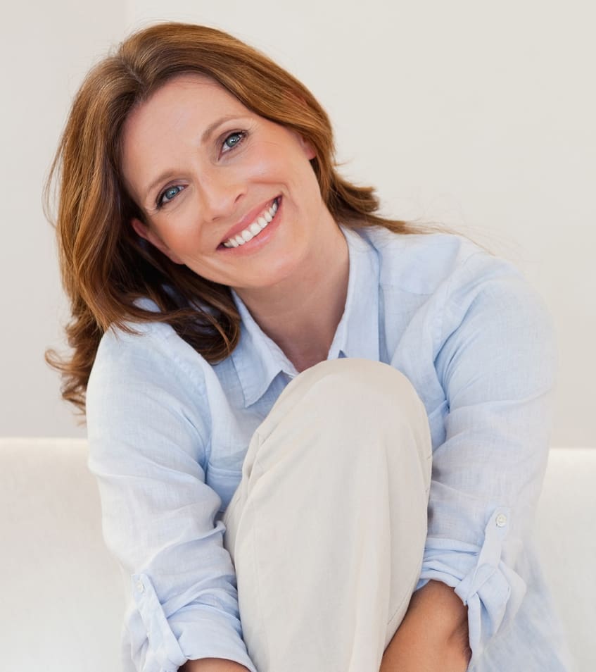 Smiling mature woman sitting on white couch Seborrheic Keratosis in Phoenix, AZ